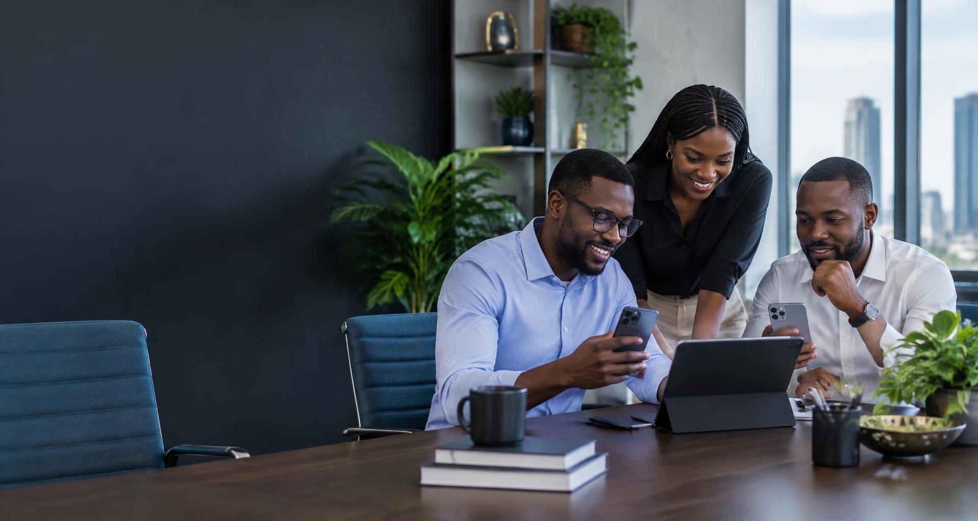 Colleagues reviewing smartphones and a tablet together in a modern office